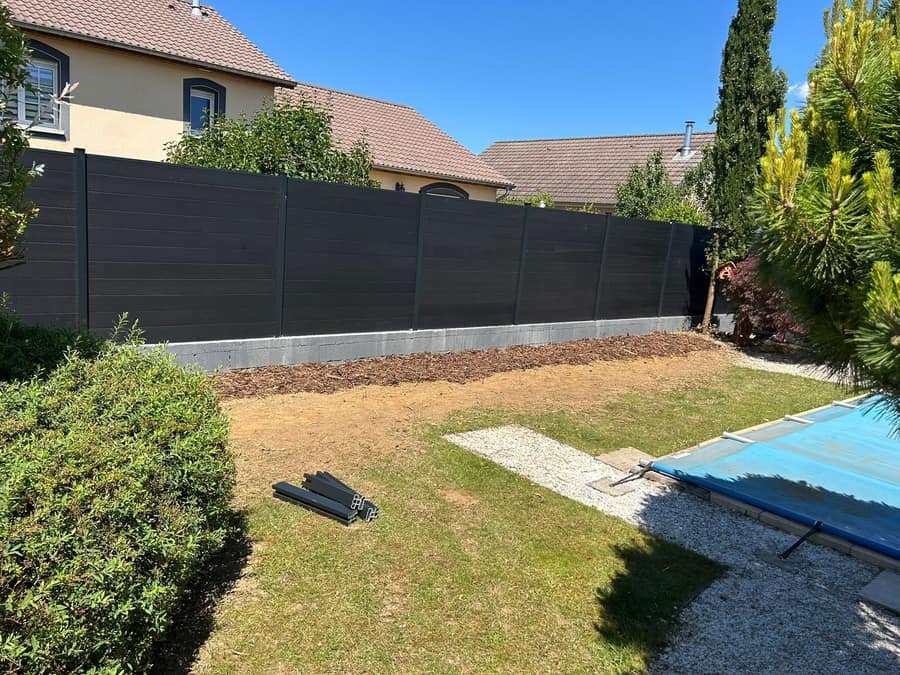 Cloture composite a lames horizontales anthracite bordant un jardin avec piscine